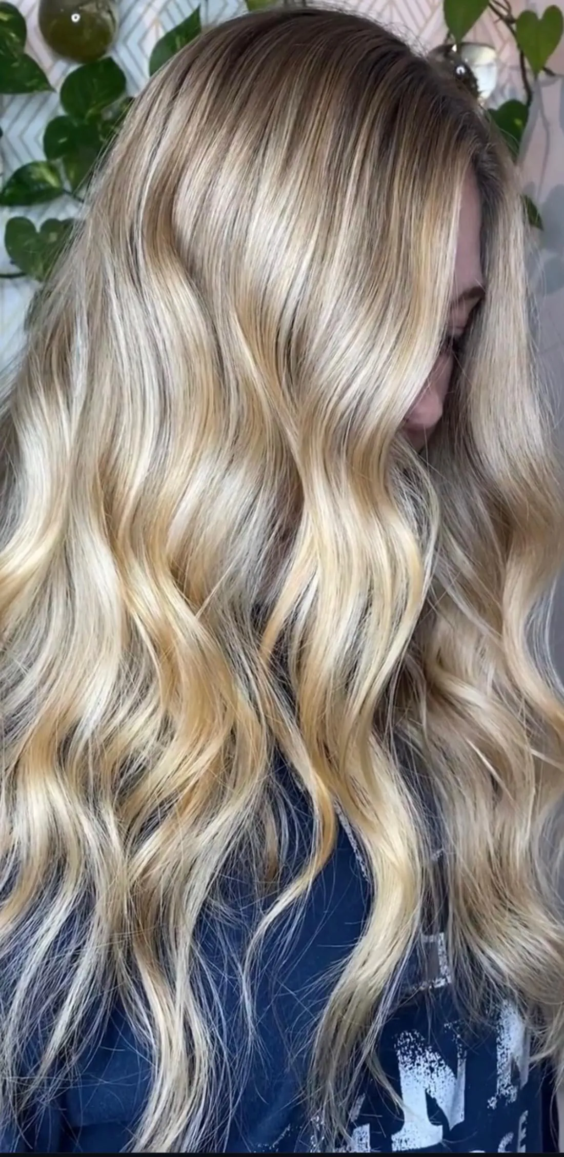 Warm golden balayage waves against the living moss wall at Sanctuary Salon and Spa, Cornelius NC